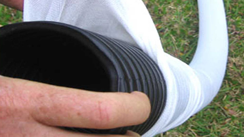 A drain sock being fitted around a pipe